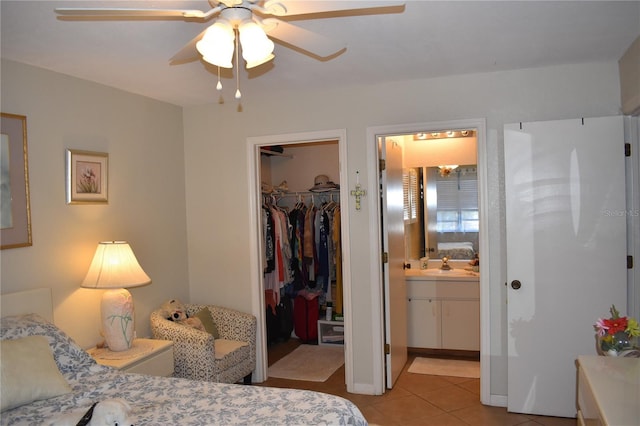 bedroom with a walk in closet, light tile patterned floors, a closet, connected bathroom, and a sink