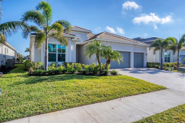 view of front of home with central AC, a garage, and a front lawn