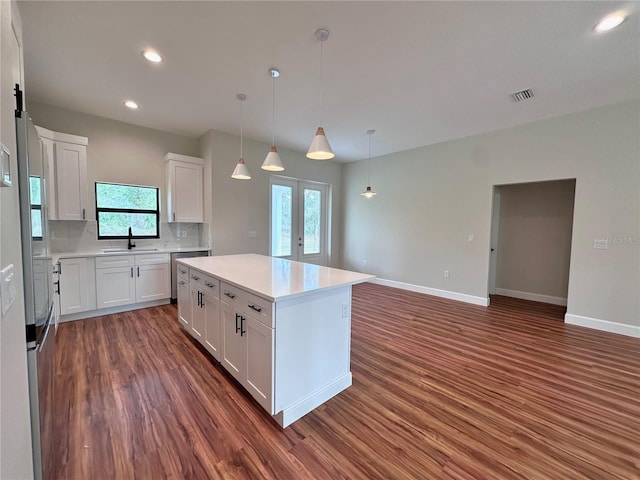 kitchen featuring a sink, backsplash, dark wood-style floors, french doors, and white cabinets