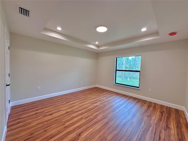 spare room with wood-type flooring and a tray ceiling