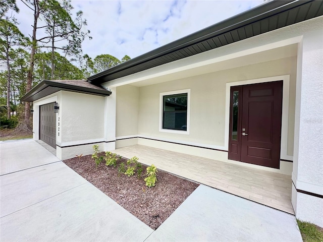 doorway to property featuring an attached garage and stucco siding