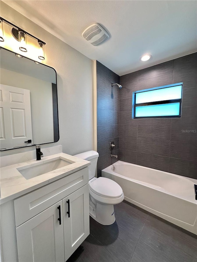 full bathroom featuring vanity, tiled shower / bath combo, tile patterned floors, and toilet