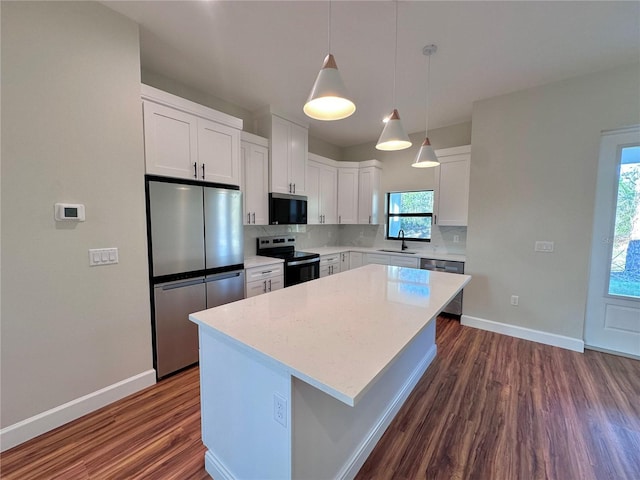 kitchen with pendant lighting, sink, appliances with stainless steel finishes, white cabinetry, and a kitchen island