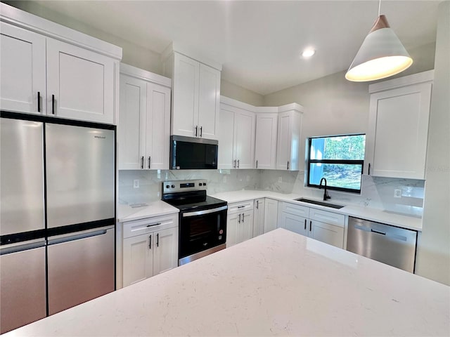 kitchen featuring light stone counters, decorative backsplash, stainless steel appliances, white cabinetry, and a sink