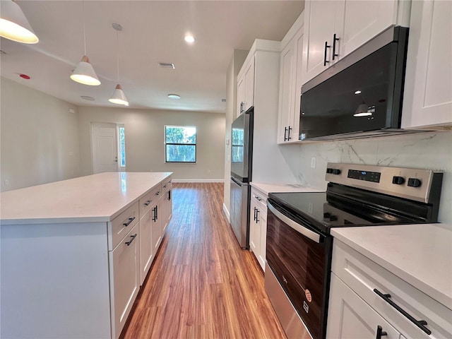 kitchen featuring stainless steel appliances, decorative backsplash, white cabinets, and decorative light fixtures