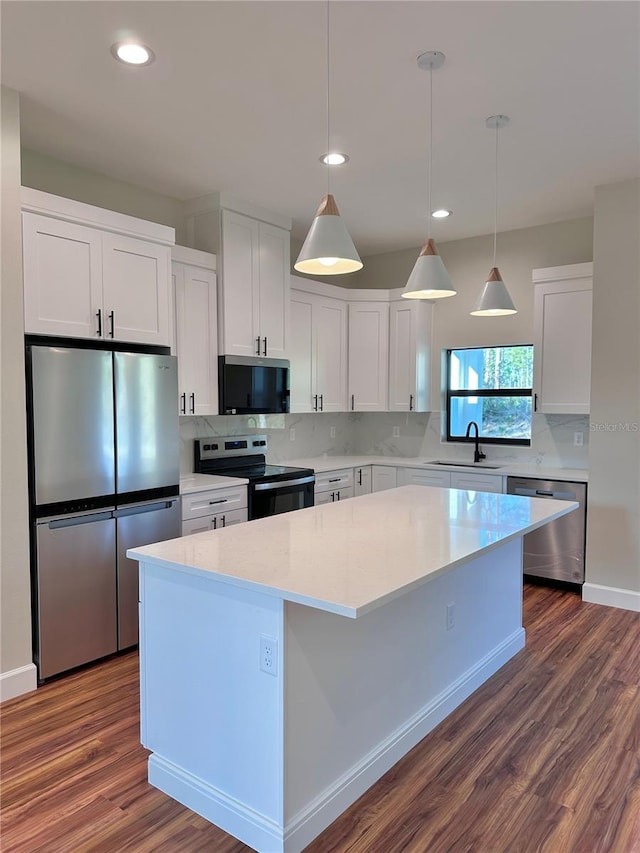 kitchen featuring a sink, white cabinets, appliances with stainless steel finishes, backsplash, and a center island