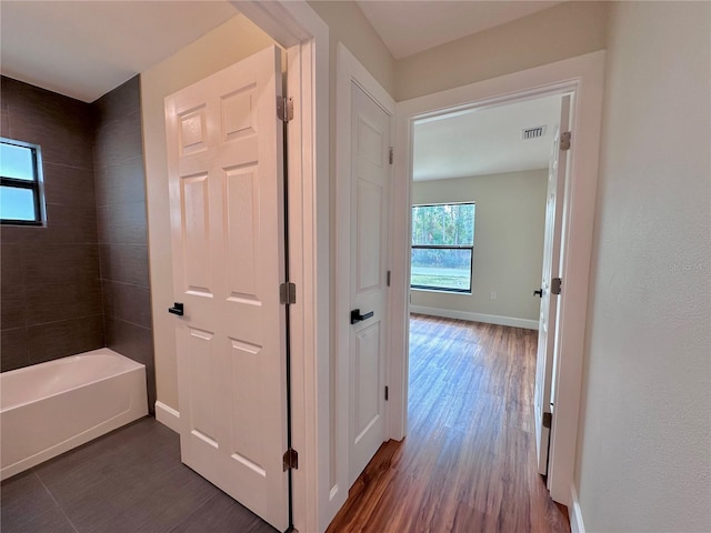 hallway featuring visible vents, dark wood-type flooring, and baseboards