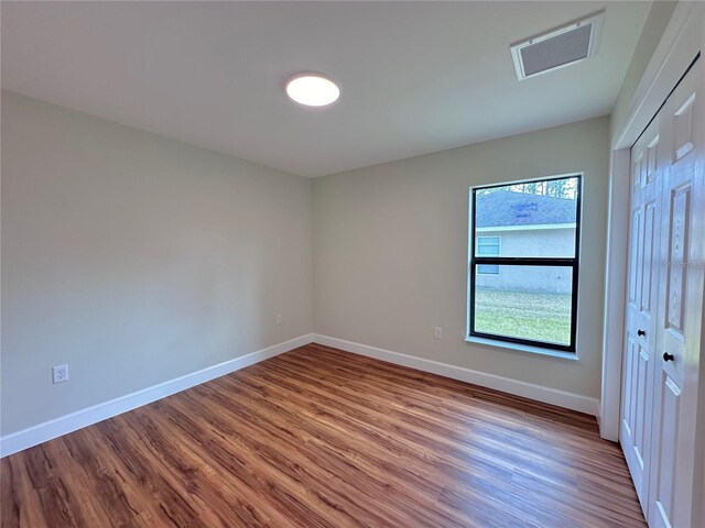 unfurnished bedroom with visible vents, baseboards, and wood finished floors