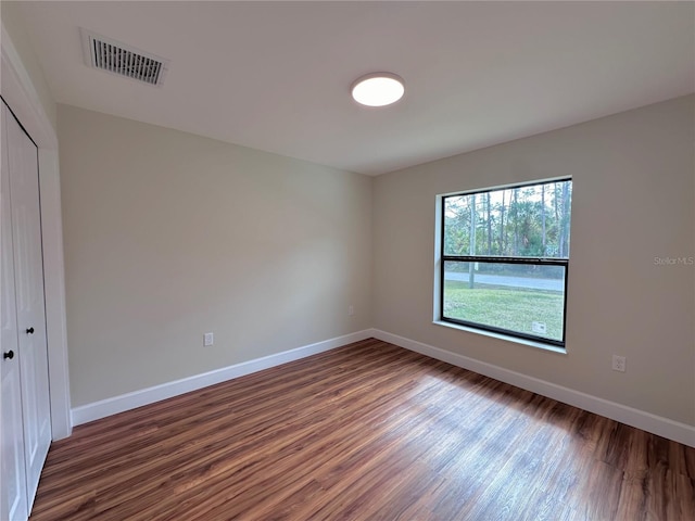 empty room featuring visible vents, baseboards, and wood finished floors