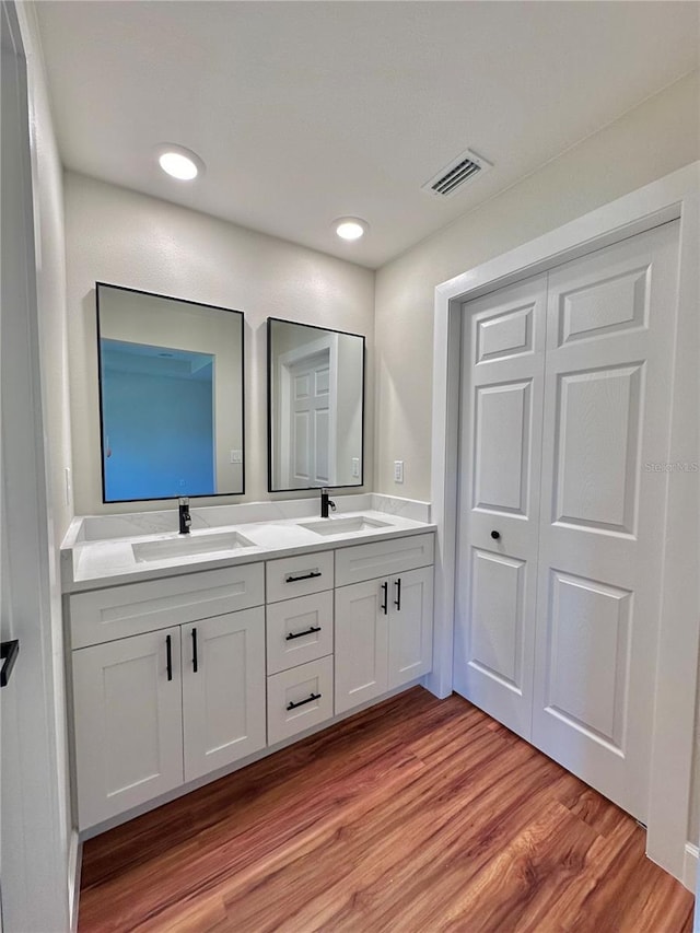 bathroom featuring double vanity, wood finished floors, visible vents, and a sink