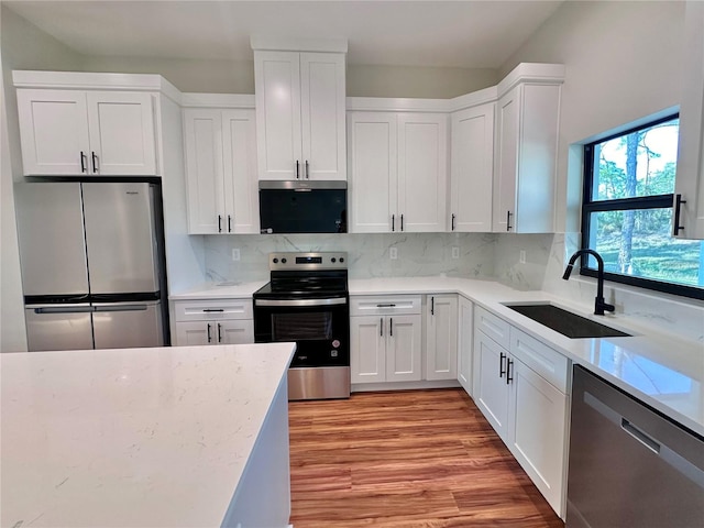 kitchen featuring white cabinetry, light stone counters, appliances with stainless steel finishes, and a sink