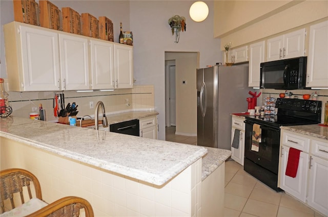 kitchen with black appliances, kitchen peninsula, and white cabinets