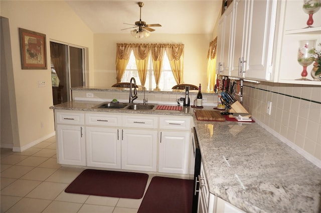 kitchen with vaulted ceiling, sink, white cabinets, and decorative backsplash