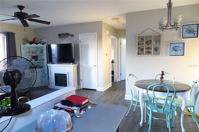 dining space with dark hardwood / wood-style flooring and ceiling fan with notable chandelier