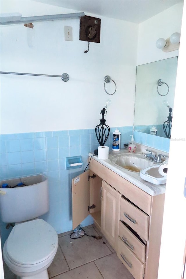 bathroom with vanity, tile patterned floors, tile walls, and toilet