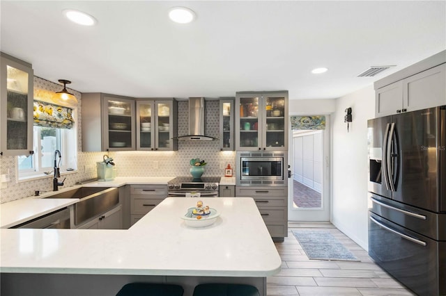 kitchen with sink, backsplash, stainless steel appliances, decorative light fixtures, and wall chimney exhaust hood