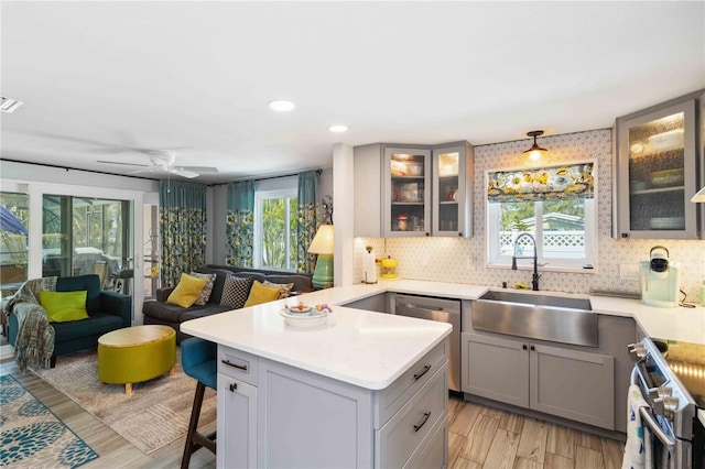 kitchen with gray cabinetry, sink, stainless steel appliances, and a kitchen bar