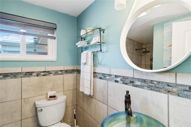 bathroom featuring toilet, sink, and tile walls