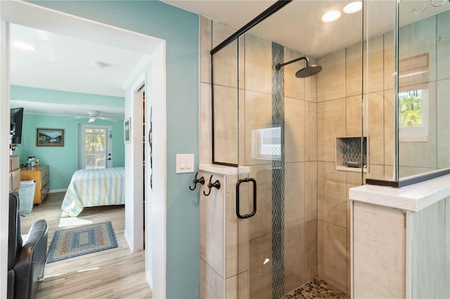 bathroom featuring ceiling fan, a shower with door, and hardwood / wood-style floors