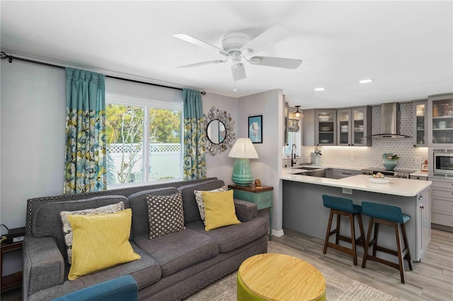 living room with sink, light hardwood / wood-style flooring, and ceiling fan