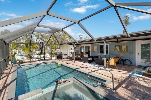 view of pool with glass enclosure, a grill, a patio area, a jacuzzi, and an outdoor living space with a fire pit