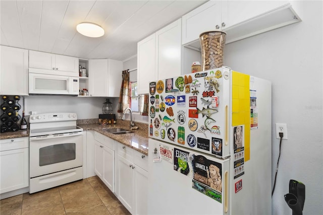 kitchen featuring sink, white appliances, light tile patterned floors, dark stone countertops, and white cabinets