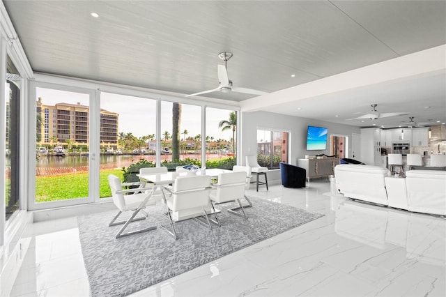 sunroom / solarium featuring a water view and ceiling fan