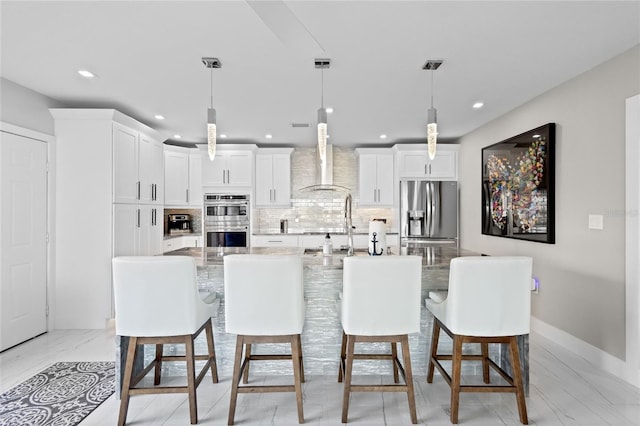 kitchen with a kitchen island with sink, decorative light fixtures, and stainless steel appliances