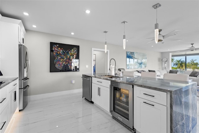 kitchen featuring pendant lighting, sink, stainless steel appliances, white cabinets, and beverage cooler