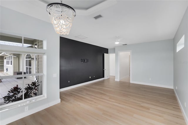 spare room with ceiling fan with notable chandelier and light hardwood / wood-style floors