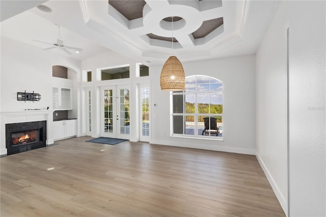 unfurnished living room featuring a high end fireplace, light hardwood / wood-style floors, french doors, and ceiling fan