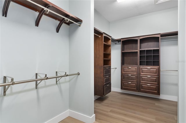 walk in closet with light hardwood / wood-style flooring