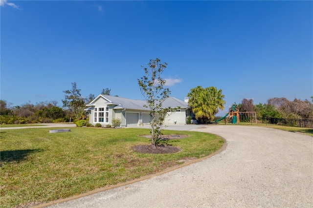 ranch-style home featuring a garage, a front yard, and a playground