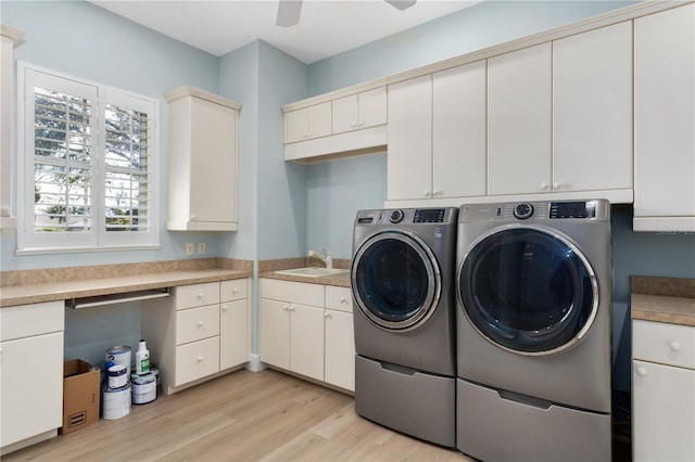 clothes washing area featuring washer and dryer, sink, cabinets, ceiling fan, and light hardwood / wood-style flooring