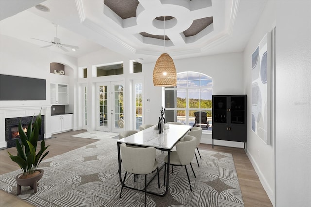 dining area featuring a premium fireplace, light hardwood / wood-style flooring, french doors, and a high ceiling