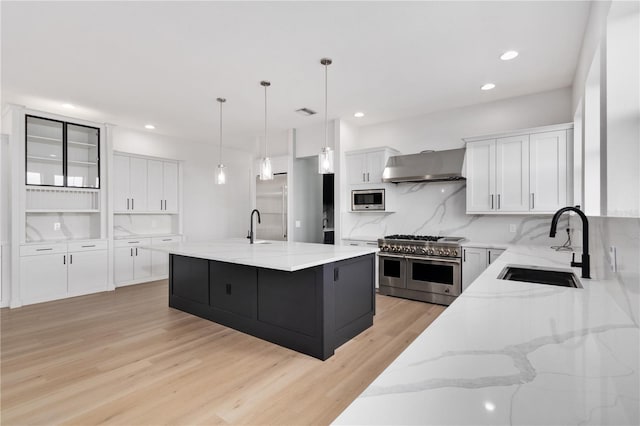 kitchen with sink, white cabinetry, built in appliances, a large island, and wall chimney range hood