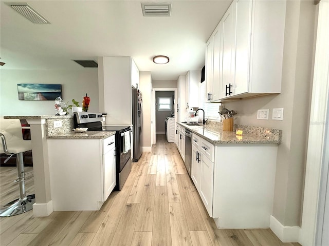 kitchen featuring stainless steel appliances, sink, white cabinets, and light stone counters