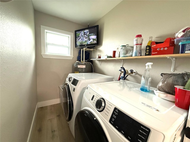 clothes washing area featuring hardwood / wood-style flooring, independent washer and dryer, and water heater