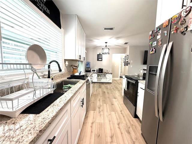 kitchen featuring stainless steel appliances, decorative light fixtures, light hardwood / wood-style flooring, and white cabinets