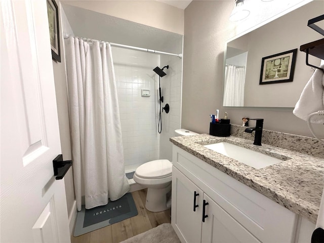 bathroom with toilet, hardwood / wood-style floors, vanity, and walk in shower