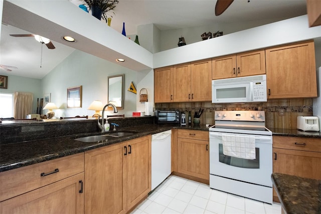 kitchen featuring ceiling fan, sink, white appliances, and dark stone counters