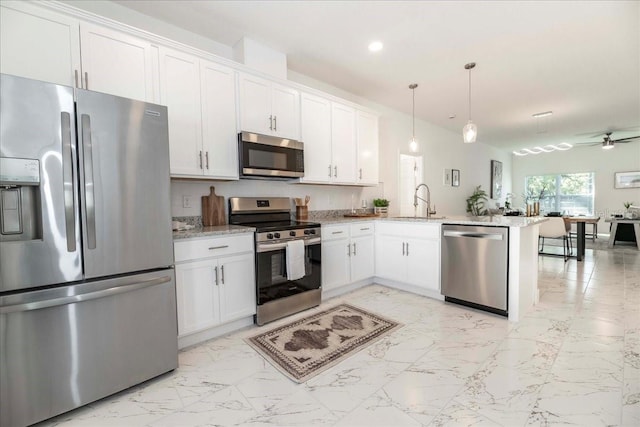 kitchen featuring pendant lighting, stainless steel appliances, kitchen peninsula, and white cabinets