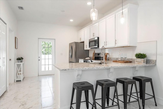 kitchen featuring decorative light fixtures, white cabinetry, kitchen peninsula, stainless steel appliances, and light stone countertops