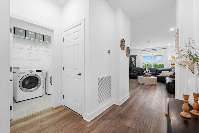 clothes washing area featuring wood-type flooring, washing machine and dryer, and ceiling fan