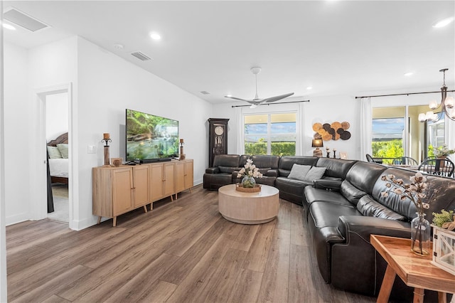 living room featuring ceiling fan with notable chandelier, hardwood / wood-style floors, and a wealth of natural light