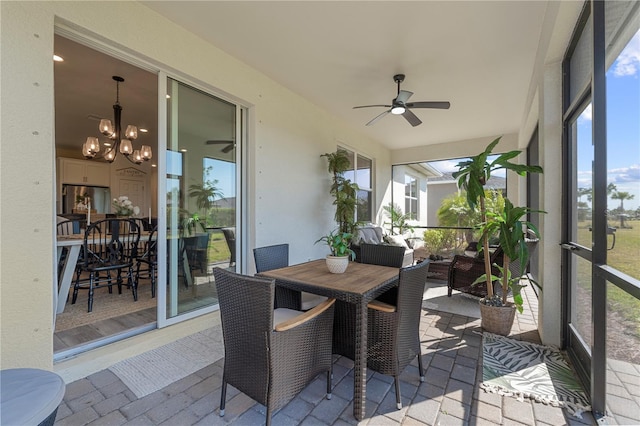 sunroom with ceiling fan with notable chandelier