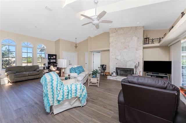 living room with dark hardwood / wood-style floors, ceiling fan, a stone fireplace, and high vaulted ceiling