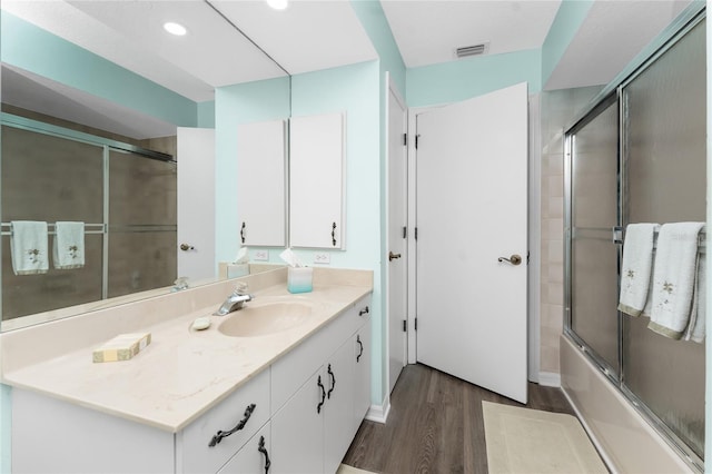 bathroom featuring vanity, hardwood / wood-style flooring, and combined bath / shower with glass door