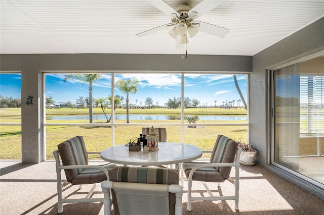 sunroom / solarium with ceiling fan and a water view