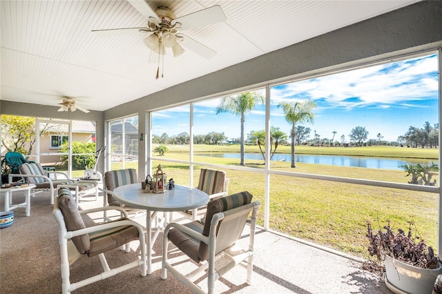 sunroom / solarium featuring ceiling fan and a water view